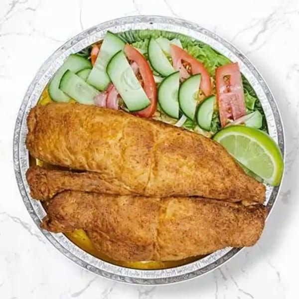 Fried fish fillets with a side salad of lettuce, tomatoes, cucumbers, and a lime wedge in a foil container.