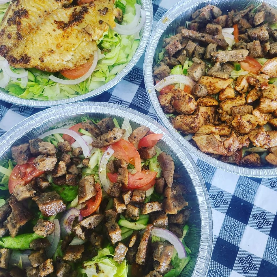 Three foil containers of Big Apple's halal salads with grilled chicken, gyro meat, and fish.